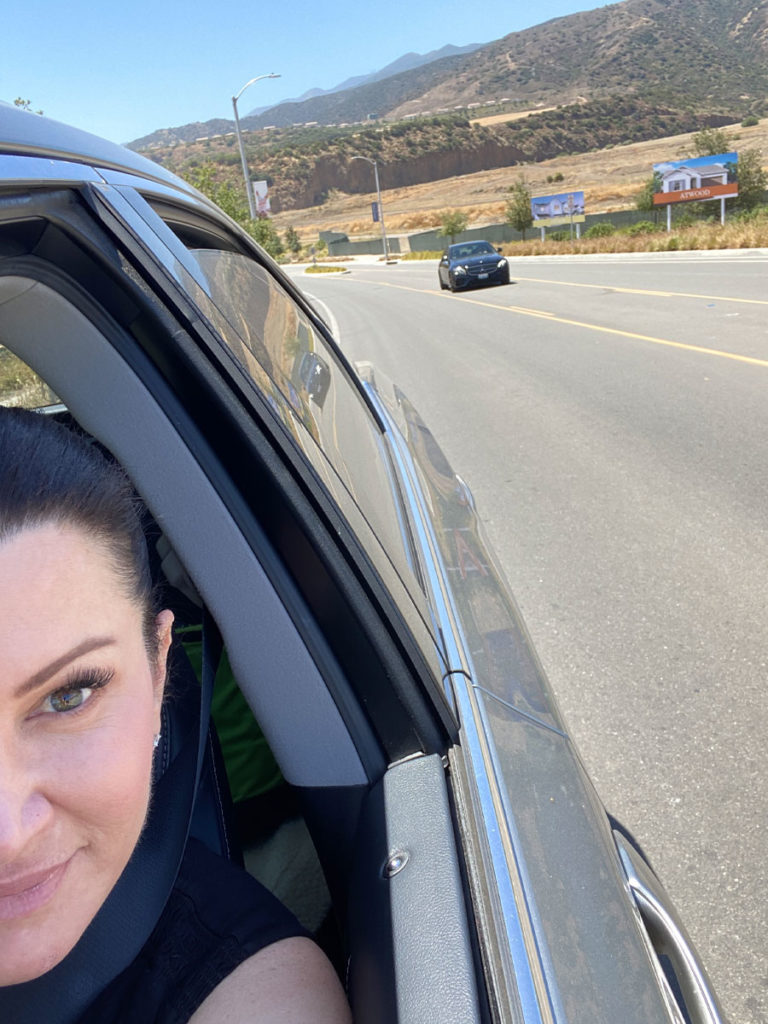 Selfie of Jen Stoddard in her car, pulled over on the side of the road, with another car in the background.