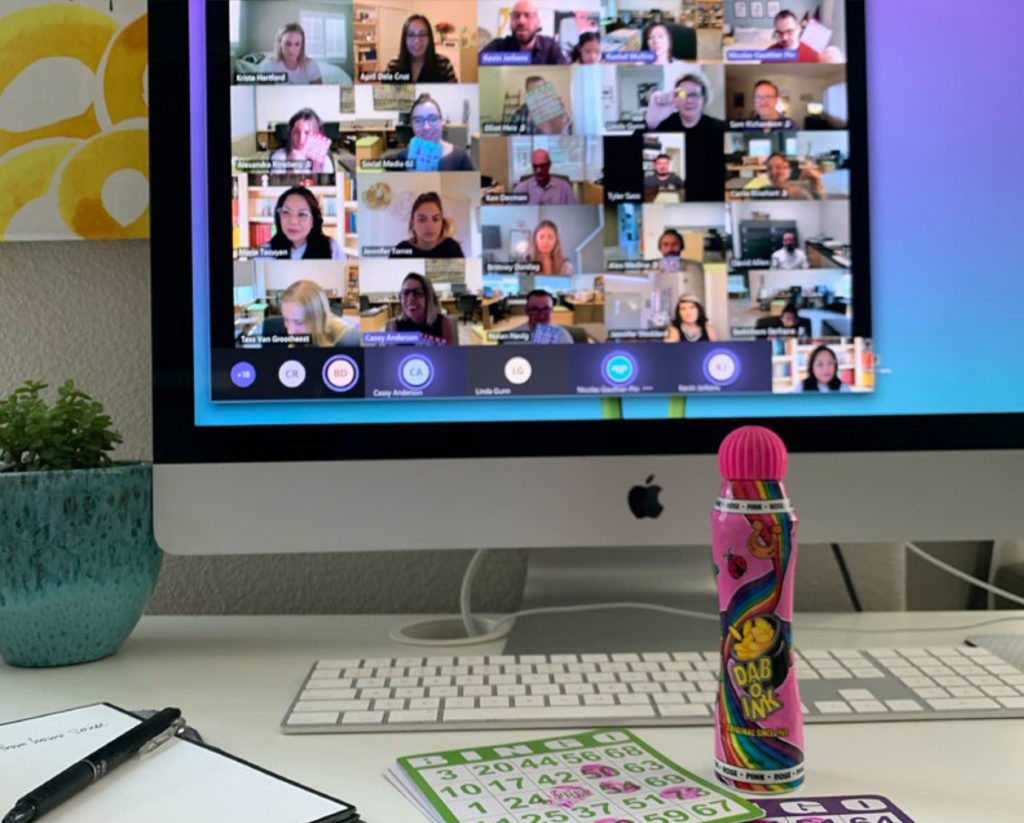 A computer showing the GJ team playing bingo on a video call. Bingo cards and a bingo dabber in the foreground.